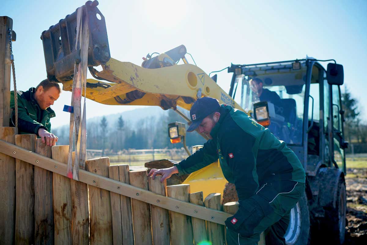 Zaunbau aus Holz mit Bagger